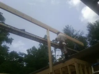 Carpenter setting a ridge beam over a new addition frame — Ice Dam Removal by Roofing Brothers in Glen Head