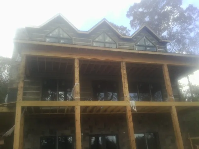 Dormers and porch framing on a large log home under construction — Roof Coating work by our crew in Glen Head