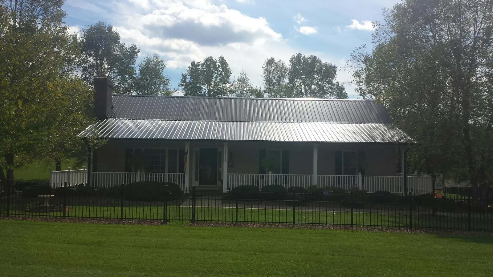 Gray metal roof on a brick ranch with a full width front porch — Gutter Guard Installation work by our crew in Glen Head