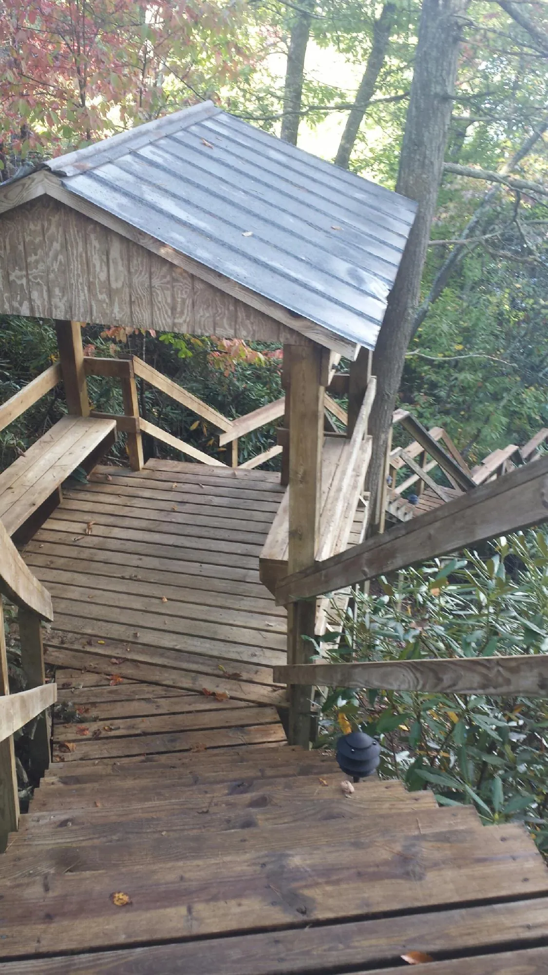 Metal roofed shelter over wooden steps on a wooded walkway — Skylight Repair & Installation work by our crew in Glen Head
